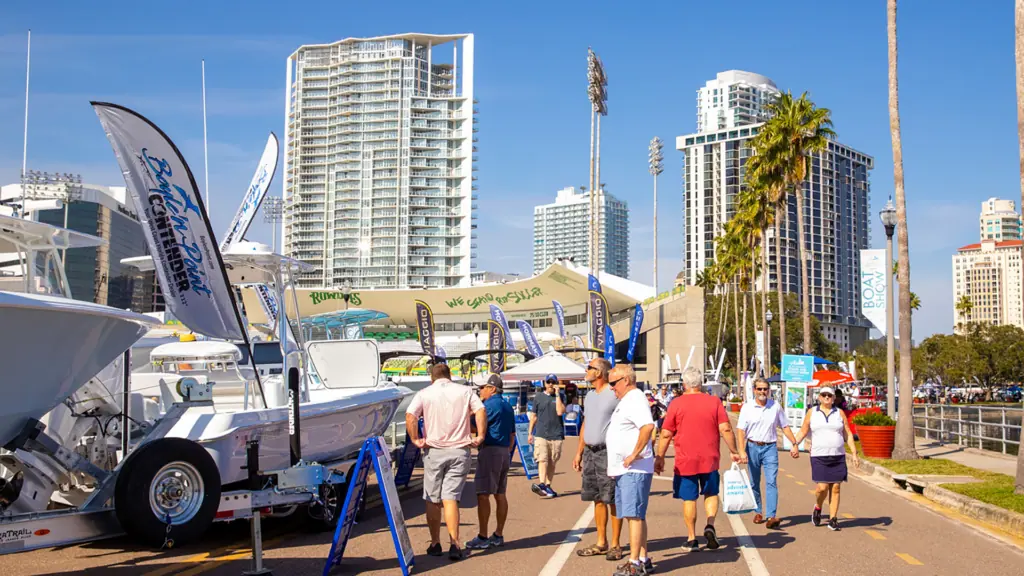 a group of people browse boats on display on the lawn at a large boat show