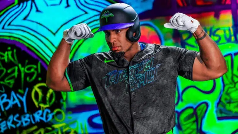 Rays baseball player Yandy Diaz models the new City Connect uniform in front of a graffiti background