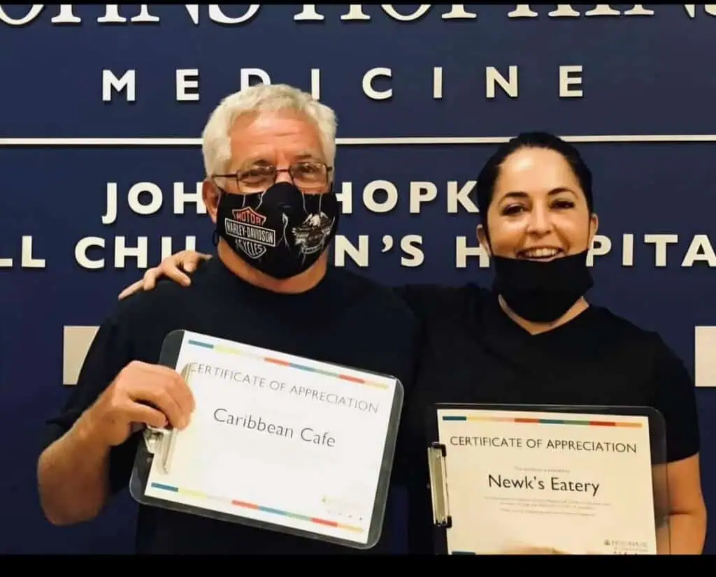 man standing beside daughter in front of hospital sign.