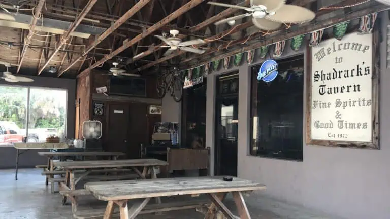The exterior of a dive bar with picnic tables