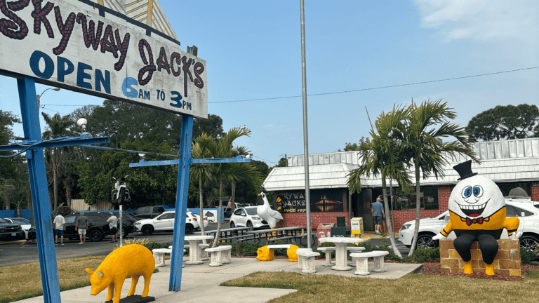 exterior of a restaurant with a large sign that reads "Skyway Jacks" and figures arranged around it