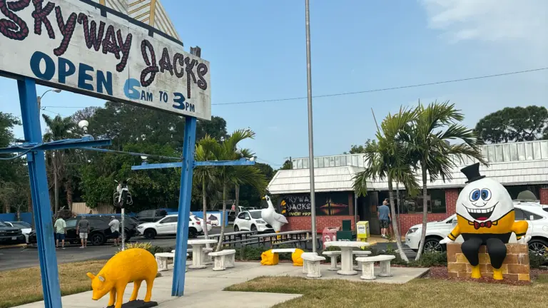 exterior of a restaurant with a large sign that reads "Skyway Jacks" and figures arranged around it