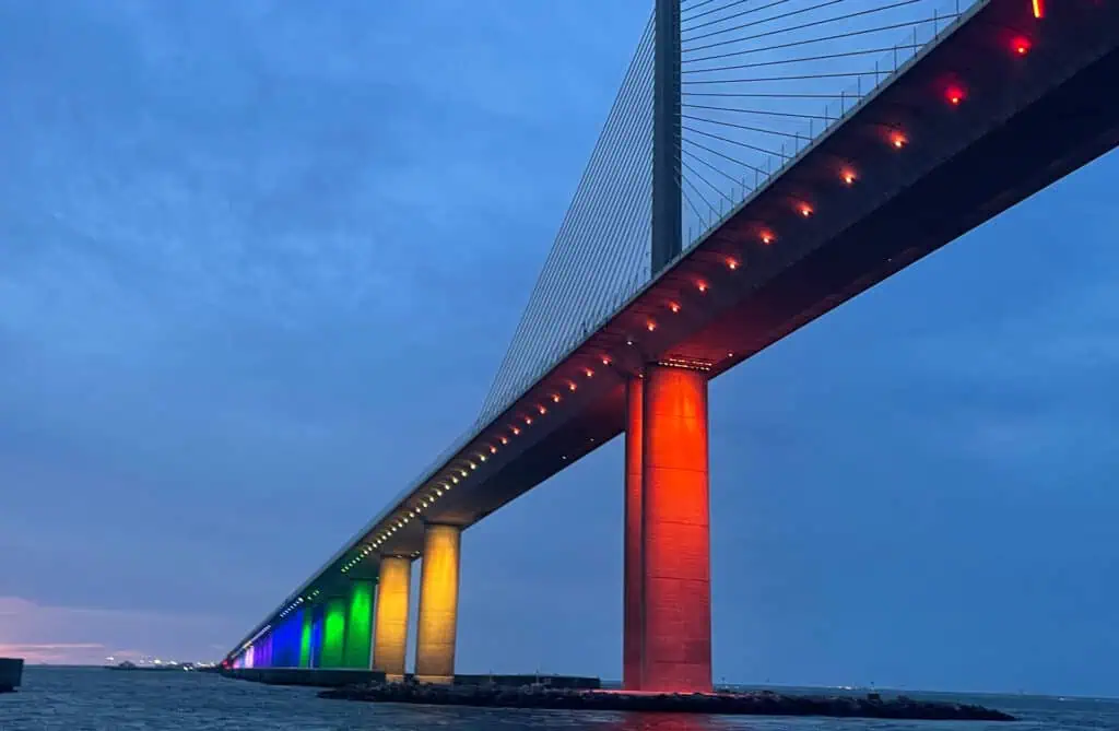 a large bridge is illuminated at night for PRIDE Month