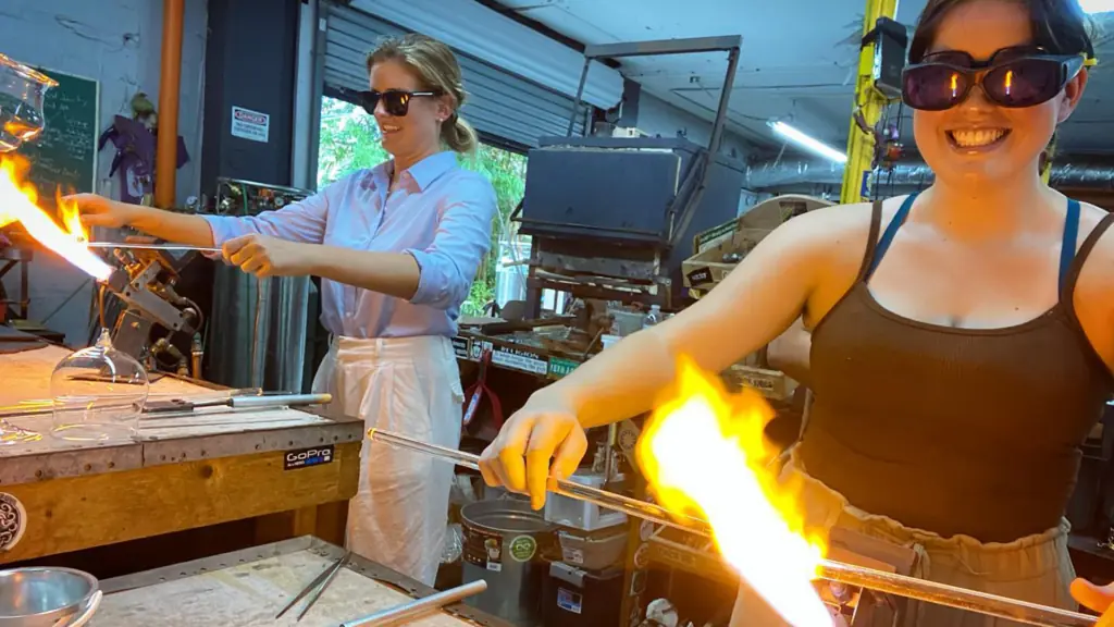 Two people operate burners at a glassblowing studio
