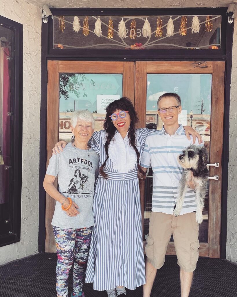 three people standing in front of building with a dog