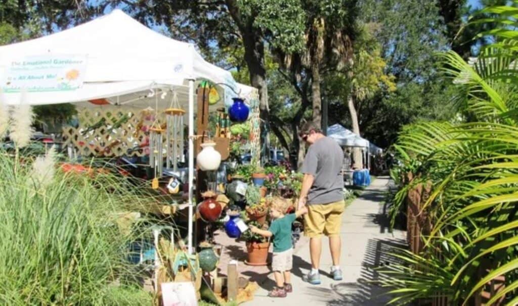 Gulfport fresh market with a father and infant in front of a stand with plants for sale