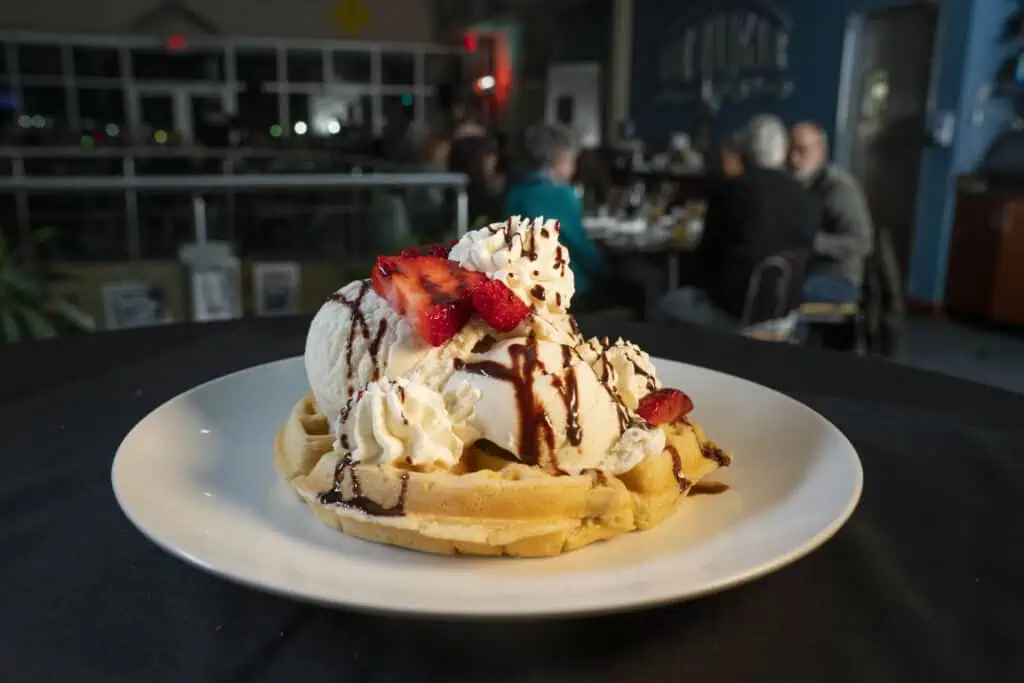 Belgian waffle with ice cream, whipped cream, and strawberries.