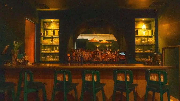 interior of a speakeasy bar with gold lights over the collection of spirits