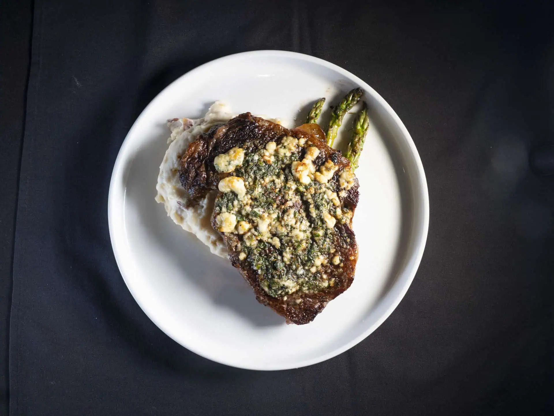 ribeye steak on a plate with mashed potatoes and asparagus. 