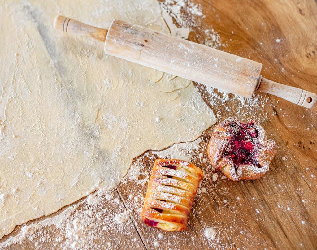 rolling pin, raw dough, and two pastries.