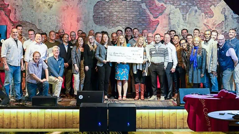 Large group of people standing on stage with the recipient of last pitch's $10,000 holding a check.