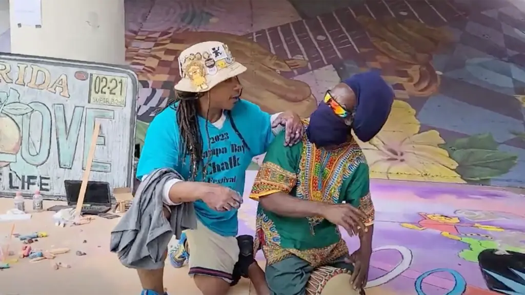 two artists stand side by side and embrace during a chalk festival