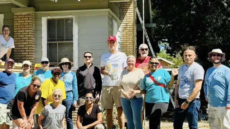 Large group of CONA volunteers stand in front of house they helped paint