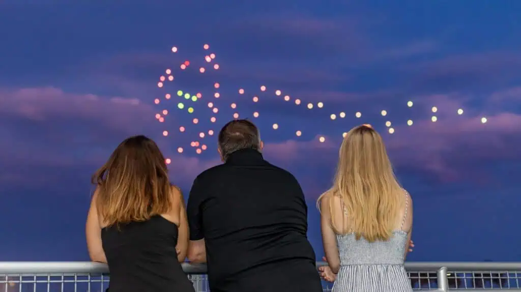 a group of people watching a drone light show on the waterfront