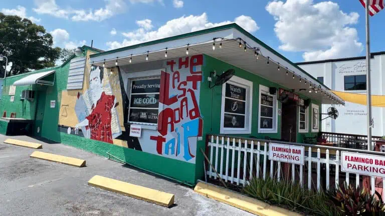 exterior of bar with mural of on the side and a pole hoisting the American flag.