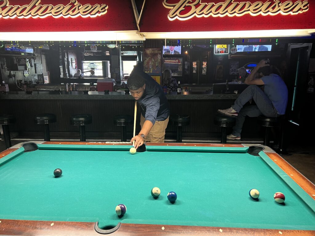 guy playing billiards inside dark bar