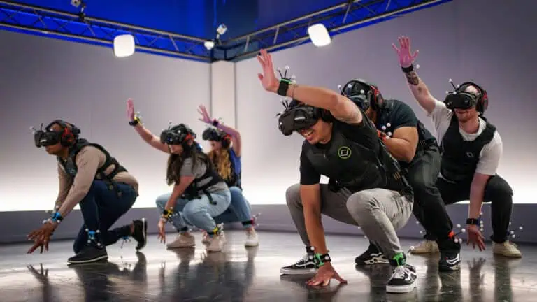 a group of virtual reality gamers gather in an arena wearing headsets