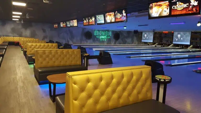 an old school bowling alley with leather booths. The lanes are lit up in blue light
