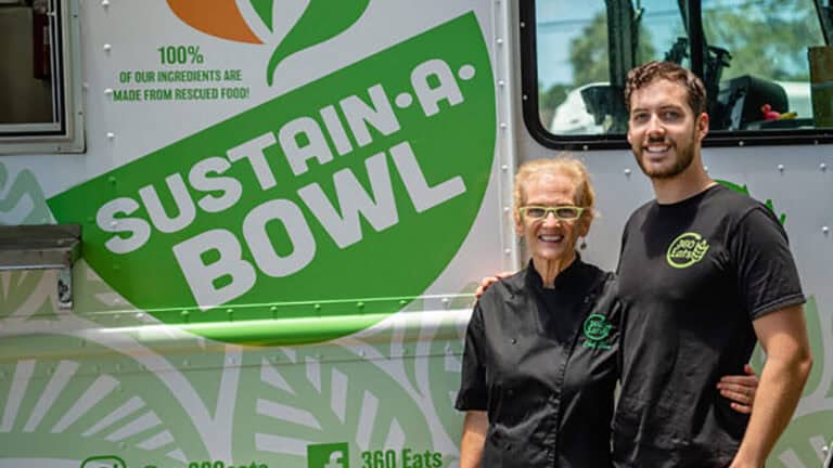 two people stand in front of a food truck with a white and green paint job