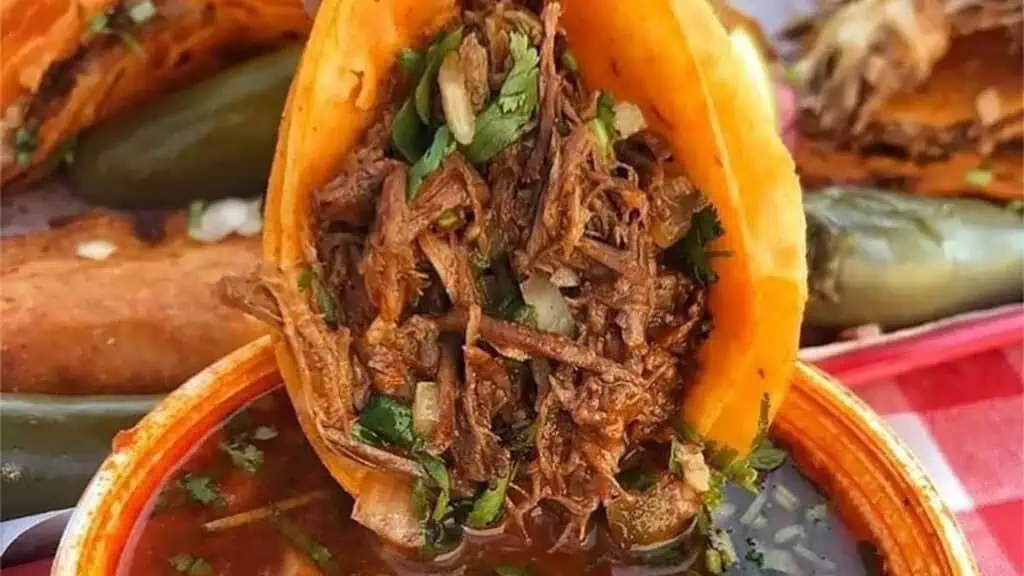 a birria taco being dipped