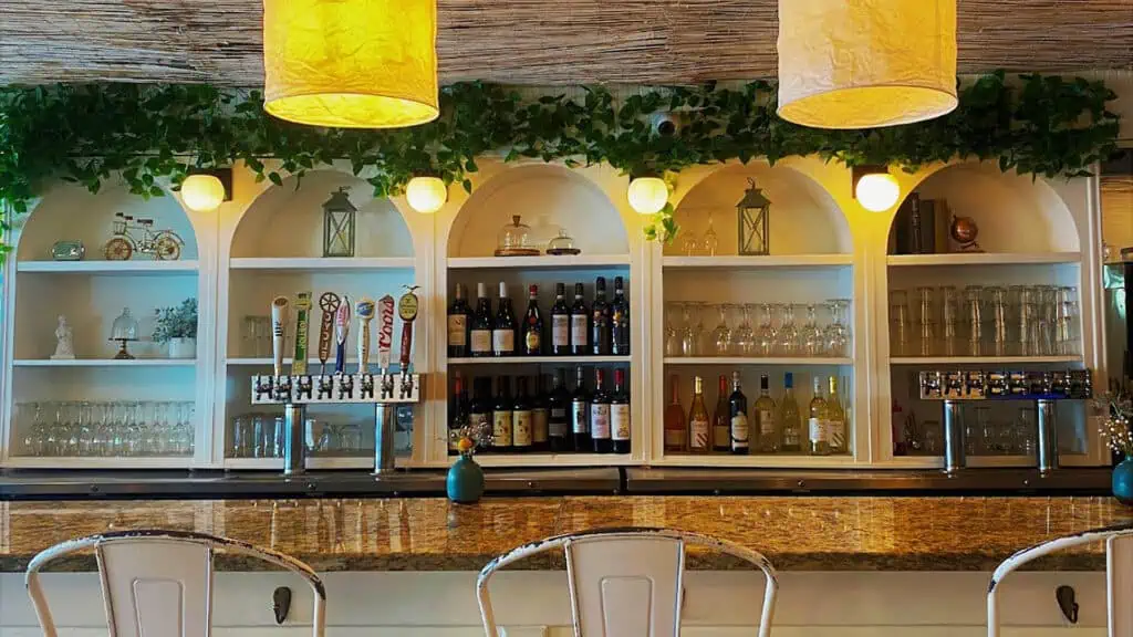 a tall bar at an Italian Restaurant. Multiple bottles of wine are visible on the shelves