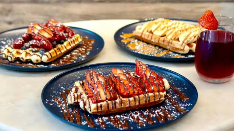 three waffles covered in fruit and honey and different syrups