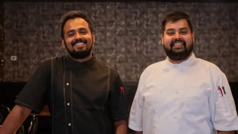 Two people standing next to one another in chef's shirts.