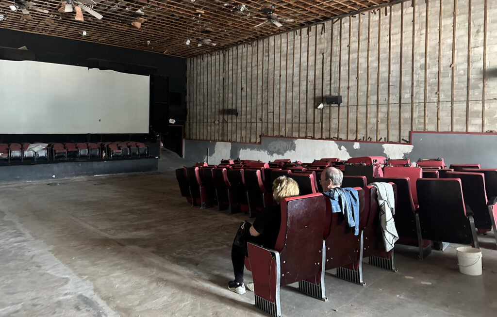 theatre screen and two people sitting in theatre seats facing it.