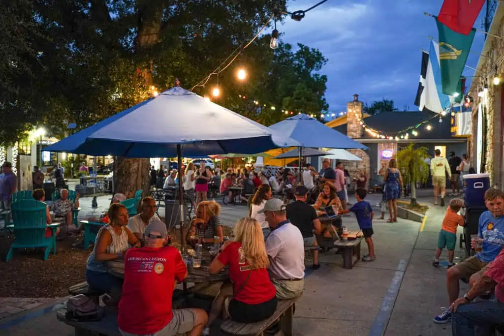 outdoor tables with blue umbrellas and people sitting