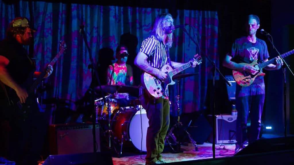 a band performs on stage under purple lights