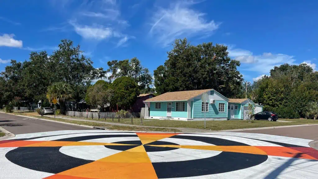 a blue home in front of a large multi color street mural