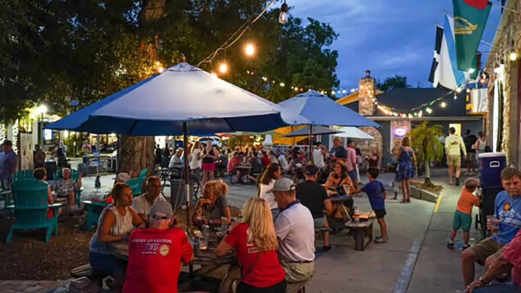 outdoor tables with blue umbrellas and people sitting