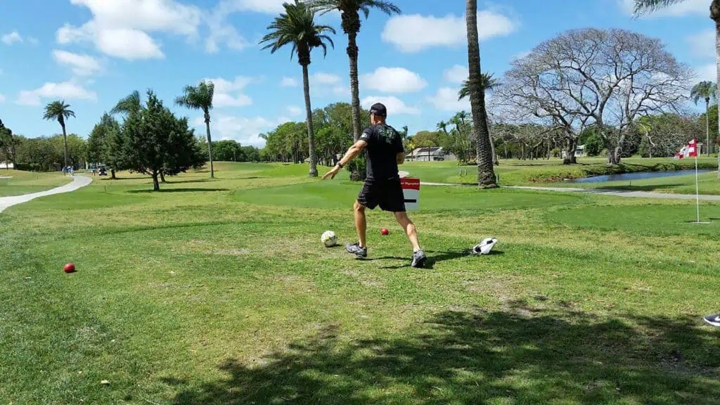 some kicks a soccer ball on a golf course