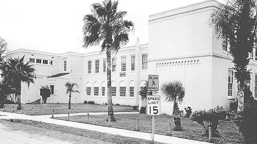 black and white photo of a high school surrounded by palm trees 