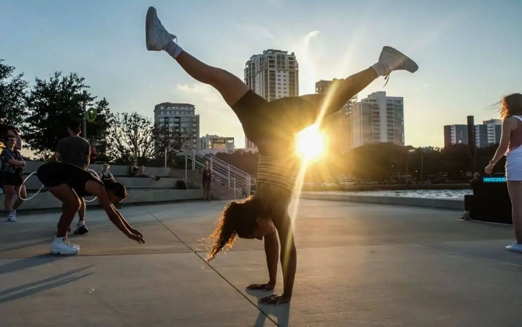 person doing hand stand with sun setting behind
