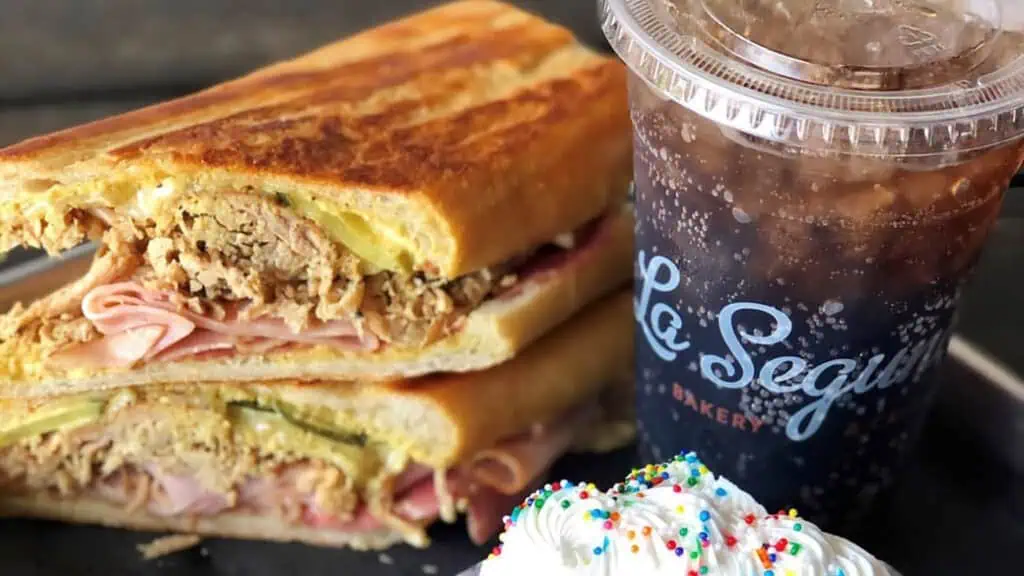 a cuban sandwich set next to an iced coffee