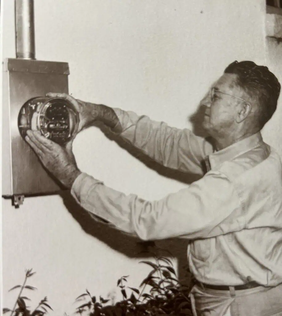 Black and white photo of a worker installing an electric meter.