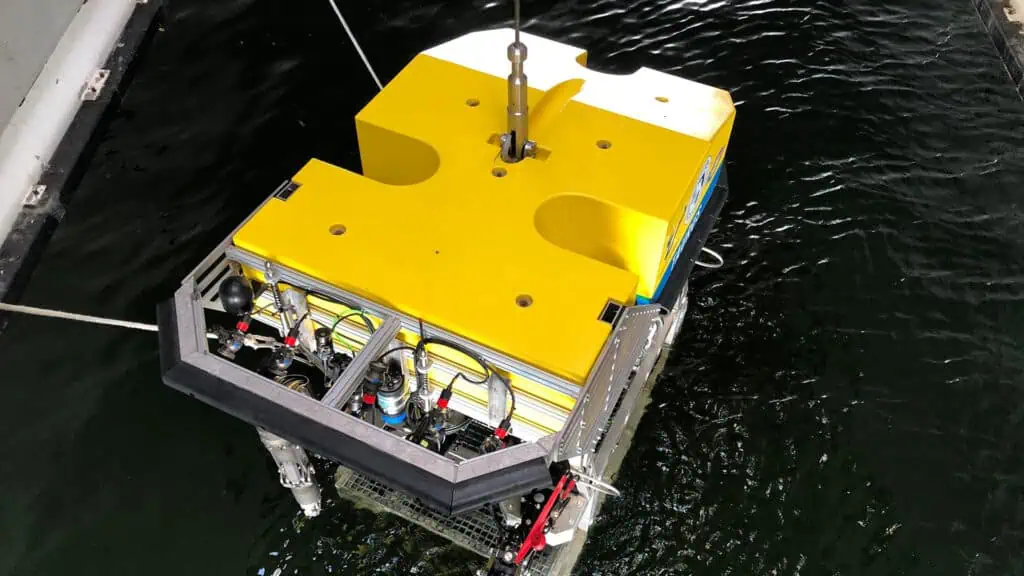 an autonomous deep sea vessel with a yellow top is dropped into the water