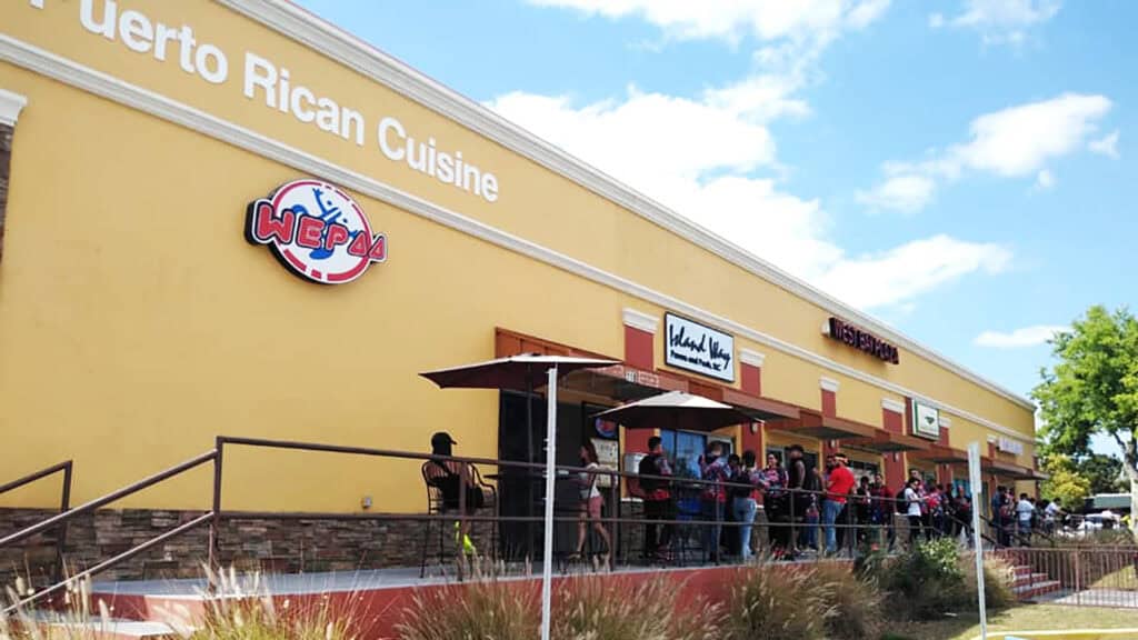 exterior of a restaurant with people lineup up outside