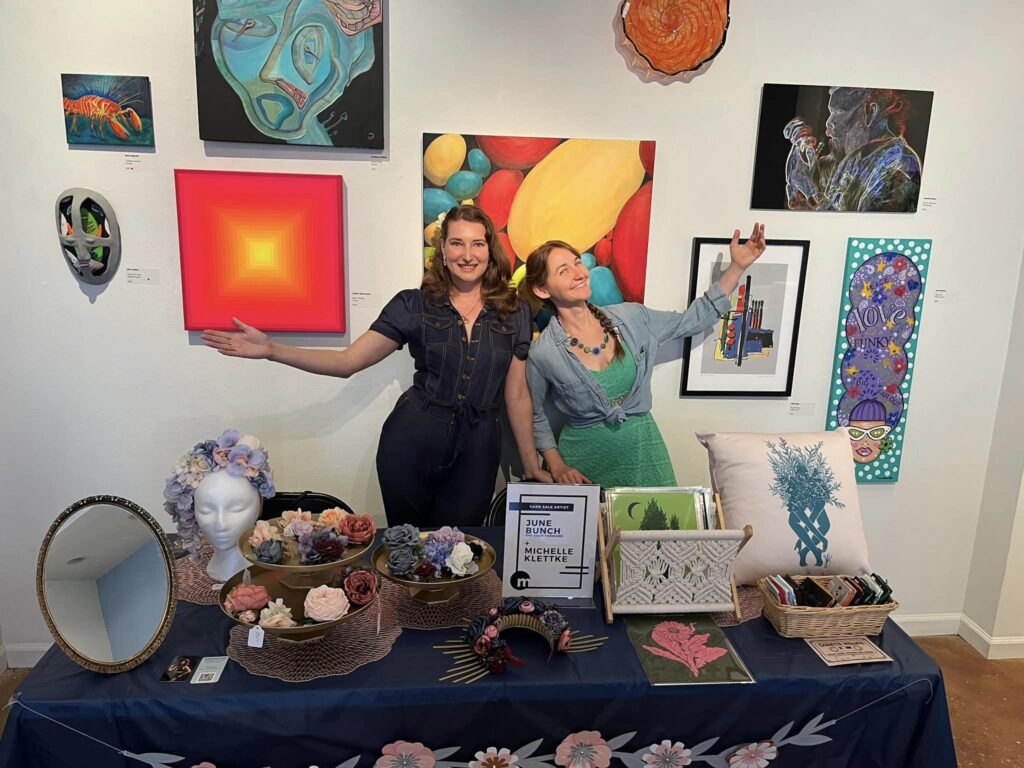 two women posing before their artwork.