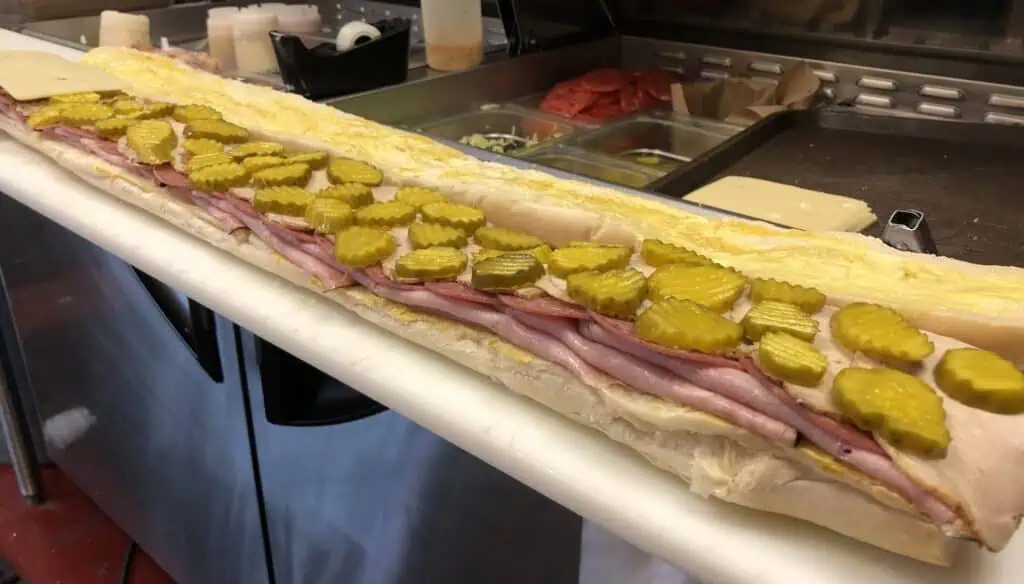 Huge sandwich open-faced on a prep table