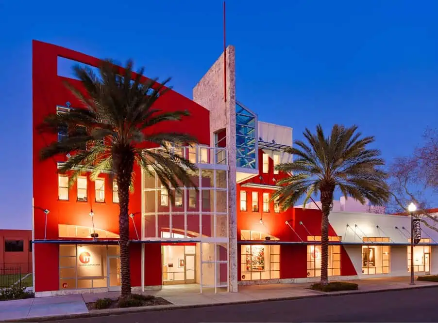 exterior of red building with two palm trees.