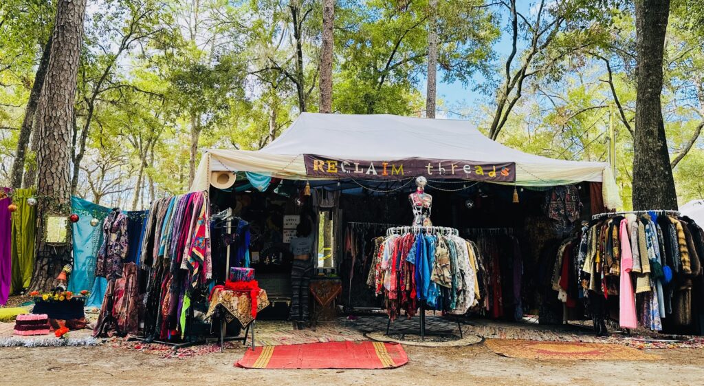 Tent outside in a forest filled with clothes.