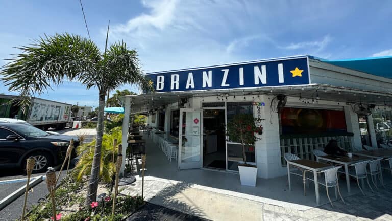 exterior of a restaurant with a large blue awning and ample outdoor seating