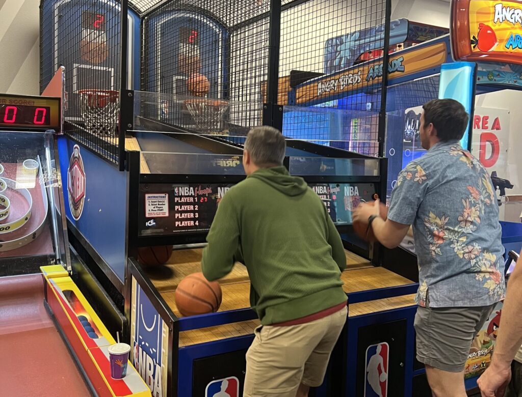 two men shooting basketballs in an arcade