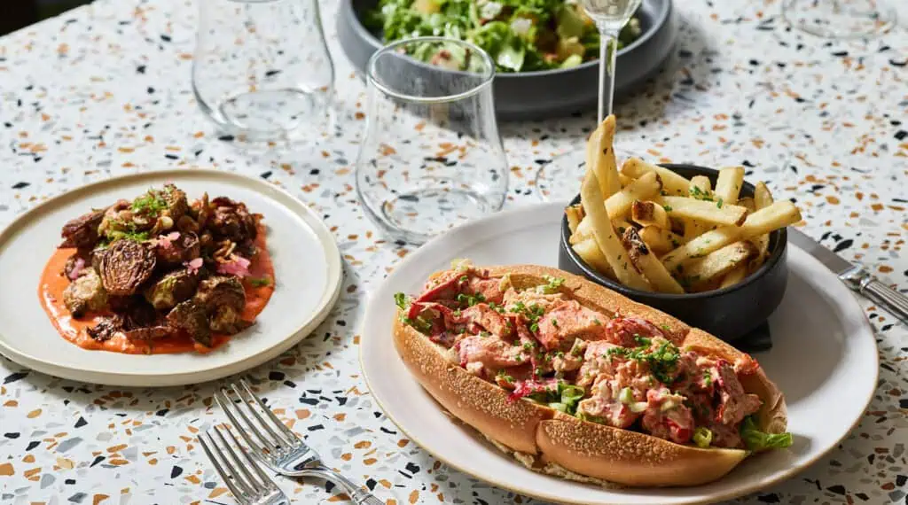 three different food items on a plate, include a lobster roll 