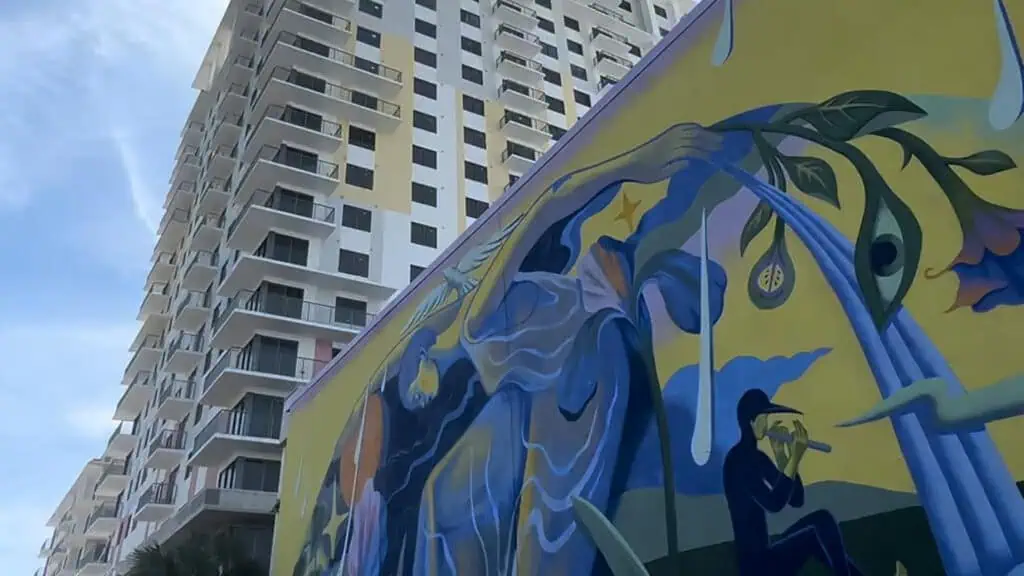 a large blue and yellow mural, and a tall residential building in the background