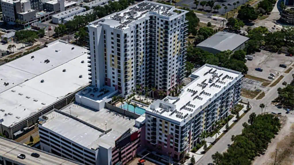 aerial view of a major mixed-use residential and retail development. a biking trail is visible on the northern side of the project