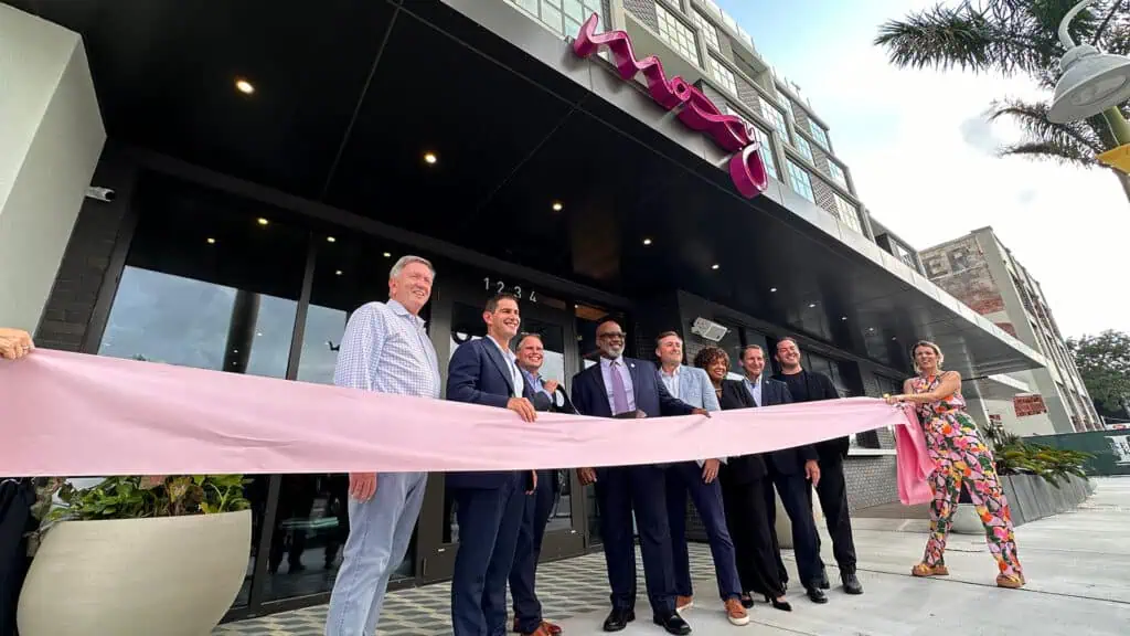 a group of people cut the ribbon on a new hotel