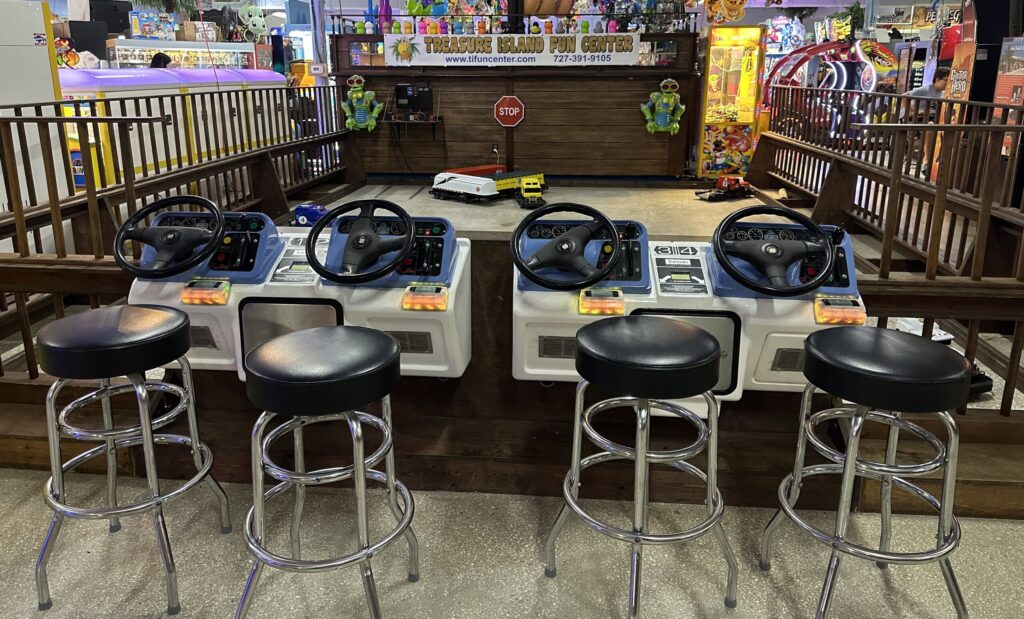 four steering wheels with bar chairs in front of game